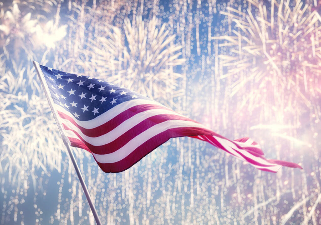 american flag waving against festive fireworks
